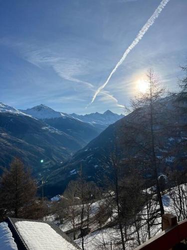 a view of a snowy mountain with the sun in the sky at Chalet Stickie by Swiss Alps Village in Hérémence