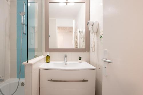 La salle de bains blanche est pourvue d'un lavabo et d'une douche. dans l'établissement Le Coquillage - 200 mètres de la Plage, à Cannes