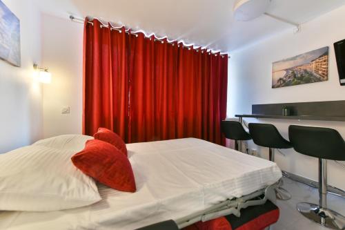 a bedroom with a bed with a red curtain at Le Coquillage - 200 mètres de la Plage in Cannes