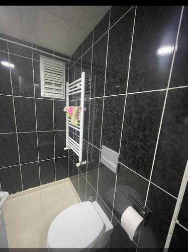 a black tiled bathroom with a toilet and a window at Merkezi konumda aile için uygun in Kilis