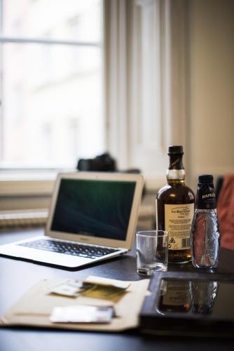 a laptop computer sitting on a table with a bottle of whiskey at Castle House Inn in Stockholm