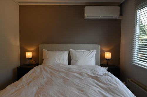 - une chambre avec un lit blanc et 2 lampes dans l'établissement Quiet and spacious holiday home, à Voorthuizen
