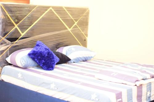 a bed with purple and white pillows on it at Royale Suites and Apartment in Abuja