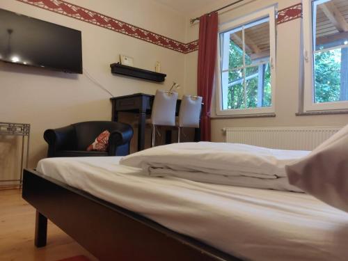 a bedroom with a bed and a chair and a television at Weingut Weinstube Weinhotel Wolf in Harxheim