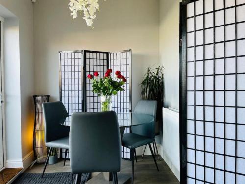 a dining room table with chairs and a vase of flowers at Fairford House - 4 Bed House - Close to the Racecourse in Cheltenham