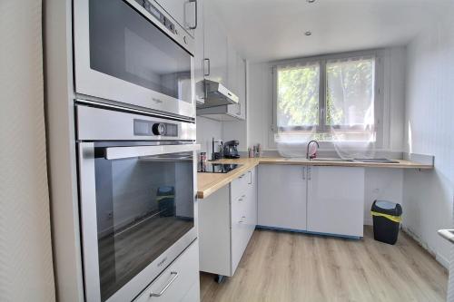 a kitchen with a stainless steel refrigerator and white cabinets at Bulle de bonheur ! Appartement avec deux chambres in Colombes