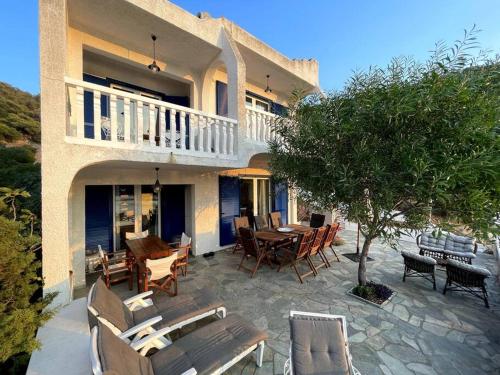 a house with a patio with chairs and a table at Villa Corali II in Pefkali