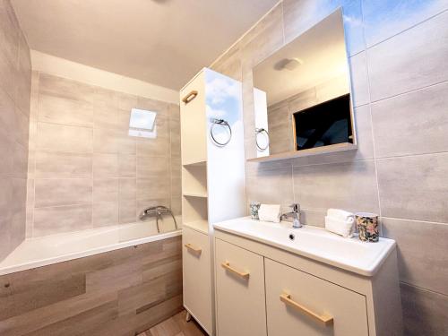ein Badezimmer mit einem Waschbecken, einem Spiegel und einer Badewanne in der Unterkunft La Casa della Felicità - WIFI - Parking - 2pers in Les Barils