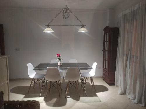 mesa de comedor con sillas blancas y luces en Vive Huelva ARAGON 4 HABITACIONES WIFI 300MB en Huelva