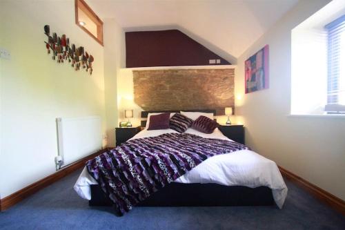 a bedroom with a large bed and a brick wall at One Bedroom Character Cottage in Farthinghoe