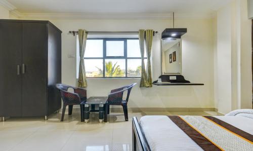 a bedroom with a table and chairs and a window at Hotel Saibala Inn in Chennai