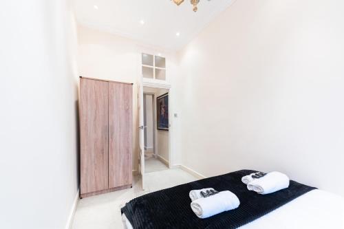 a white room with two towels on a bed at Luxury 4 bedroom flat in Sussex Gardens in London