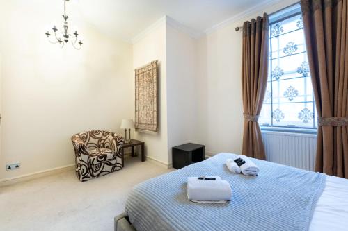 a bedroom with a bed and a chair and a window at Luxury 4 bedroom flat in Sussex Gardens in London