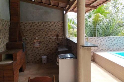 uma cozinha exterior com um lavatório e uma piscina em Casa Muro de Pedra / Cabrália em Santa Cruz Cabrália