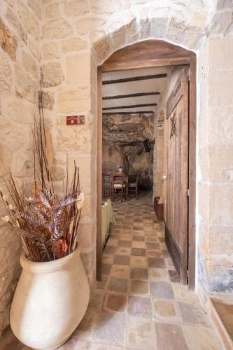 a stone hallway with a large vase with flowers in it at Si-Moutique, le Case-grotte degli Avi 2 in Modica