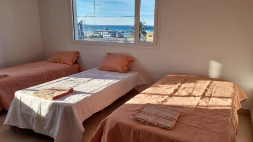 two beds in a room with a view of the ocean at Hotel Costa Ballena in Puerto Madryn