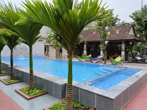 a pool with two palm trees next to a house at Tropical Valley Homestay in Phong Nha