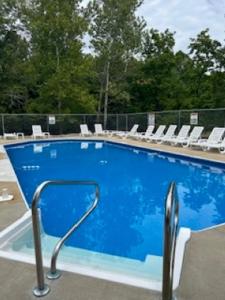 una piscina azul con sillas blancas alrededor en Arcadia Cabin #25 at Patoka 4 Seasons Resort, en Salem