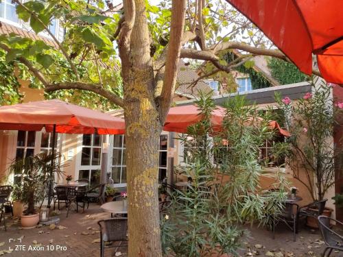 an outdoor patio with tables and chairs and an umbrella at Weingut Weinstube Weinhotel Wolf in Harxheim