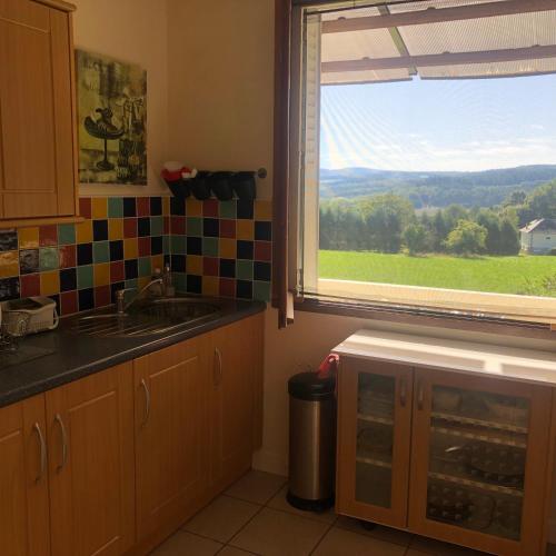 d'une cuisine avec évier et d'une fenêtre avec vue. dans l'établissement Bruyères, Myrtilles et Monédières en Corrèze, 1, à Peyrissac