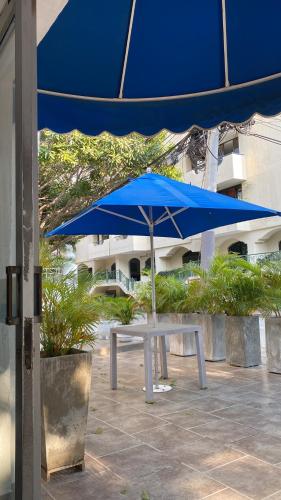 ein blauer Regenschirm neben einem weißen Tisch in der Unterkunft Hotel Casa Victoria Rodadero in Gaira