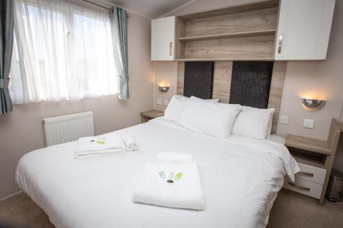 1 dormitorio con 1 cama blanca y 2 toallas en Sheerness Holiday Caravan for 6, en Sheerness