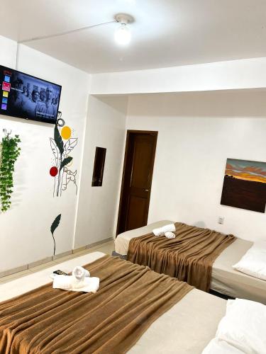 a hotel room with two beds and a flat screen tv at Pousada Marajó For You in Soure