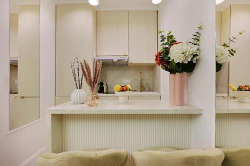 - une cuisine avec un comptoir avec 2 chaises et des fleurs dans l'établissement Bretagne Mairie du 3e, à Paris
