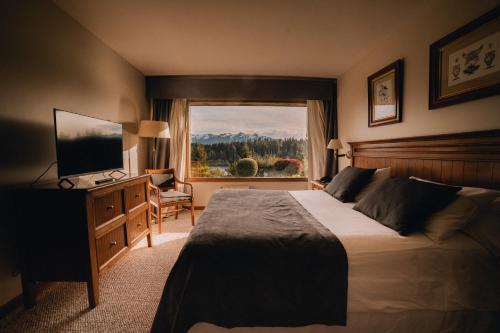 um quarto com uma cama, uma televisão e uma janela em Marinas Alto Manzano em Villa La Angostura