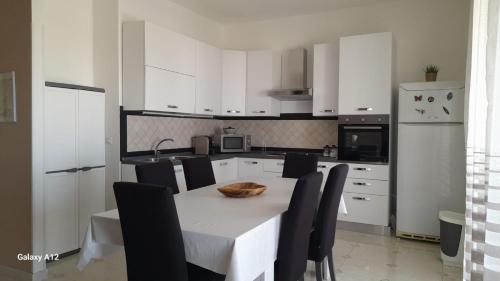 eine Küche mit einem weißen Tisch und schwarzen Stühlen in der Unterkunft Villino Lufina in Carini