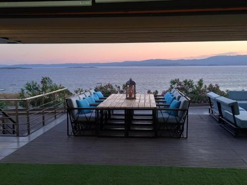 a table and chairs on a deck with a view of the water at Mavi Panorama Villa in Cesme
