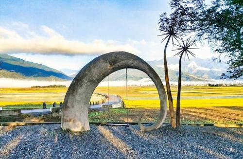 a large metal sculpture in a field with a tree at Xiaomi Courtyard B&B in Chishang