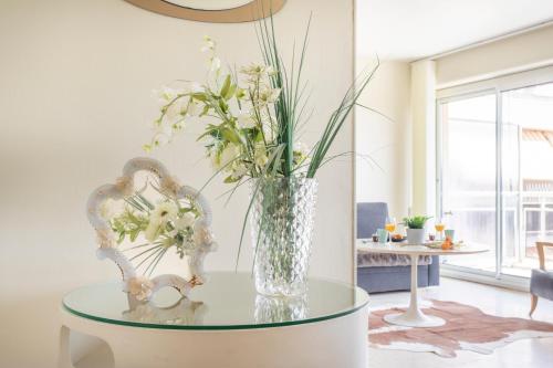 wazon kwiatów na szklanym stole w salonie w obiekcie Spacieux appartement Climatisé, lumineux, Grand Balcon, dernier étage au calme dans le parc de la Torse à 10mn à pied du centre ville w Aix-en-Provence