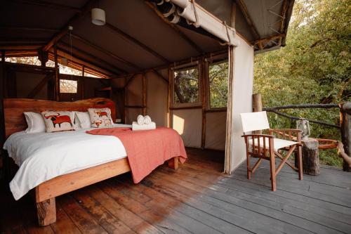 Schlafzimmer mit einem Bett auf einer Holzterrasse in der Unterkunft Kasabushi Camp in Chunga