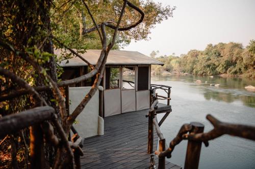 une petite maison sur un quai au bord d'une rivière dans l'établissement Kasabushi Camp, à Chunga