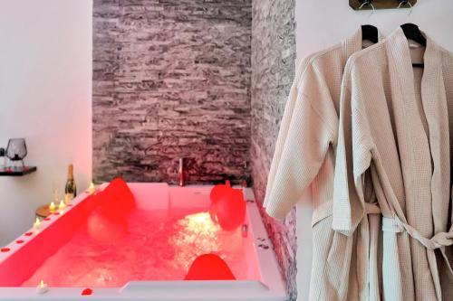 a pink tub in a bathroom with a stone wall at LE COCON- Jacuzzi & Sauna privés By SweetDreams in Le Cannet