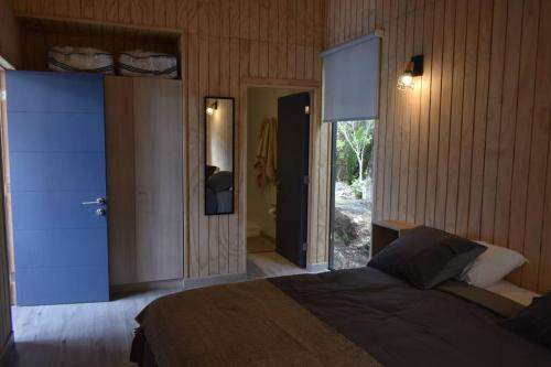 a bedroom with a bed and a door to a bathroom at Impressive Don Santiago Cabin, Chilean Patagonia. in Chaitén