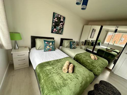 a bedroom with two beds with green sheets at Beautiful House in South Cambridge, 14-Min Drive to the City Centre, Free Parking, No Sofabeds, Sleeps 6 in Cambridge