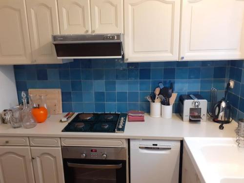 une cuisine avec des armoires blanches et un four à plaques de cuisson dans l'établissement Belle maison familiale à 3 minutes de la plage, à LʼÉpine