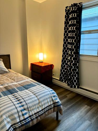 a bedroom with a bed and a window with a lamp at Iron Bound Gem in Newark