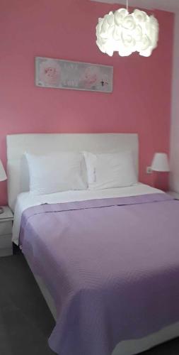 a bedroom with a white bed and a pink wall at Ormos View Apartments in Ormos Panagias