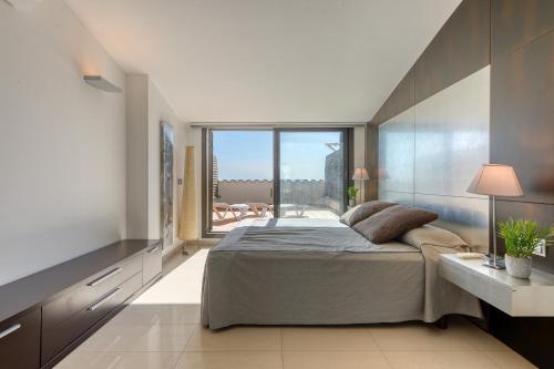 sypialnia z dużym łóżkiem i dużym oknem w obiekcie Mileni Atico Duplex Roses - Immo Barneda w mieście Roses