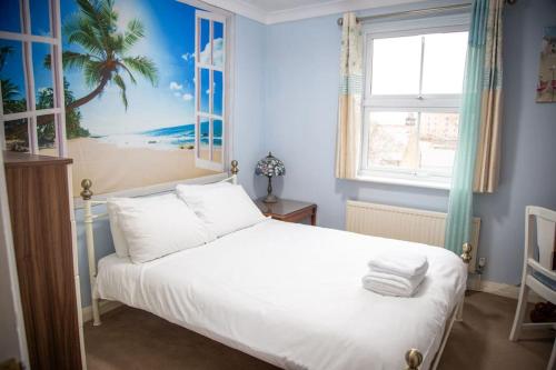 a bedroom with a bed with a palm tree painting on the wall at Cosy and Spacious House for 6 in Rochester