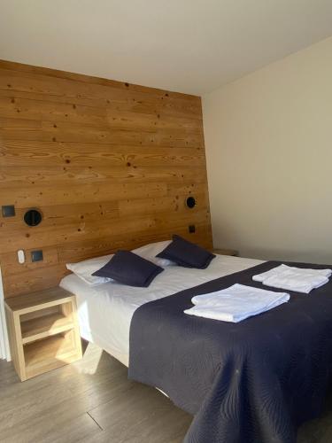 a bedroom with a large bed with a wooden wall at Hotel Le Chalet in Sainte-Marie-de-Campan