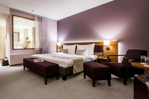 a hotel room with a large bed and a chair at Deltapark Vitalresort**** in Thun