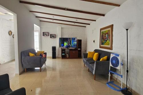 sala de estar con sofás y TV de pantalla plana. en Casa Las Lomas Huanchaco-Trujillo Piscina, en Huanchaco