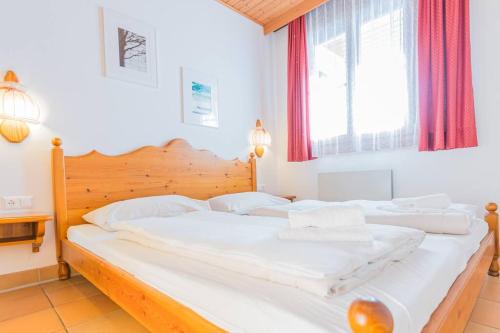 um quarto com 2 camas com lençóis brancos e uma janela em Gerlitzen Berg- und Seenurlaub em Deutschberg
