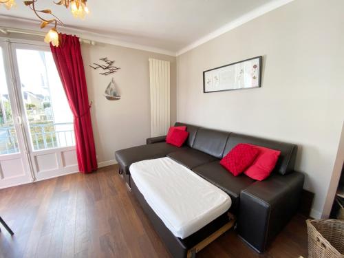 カルナックにあるKermario 1, bel appartement à Carnac, Wifi inclusのリビングルーム(赤い枕と黒い革張りのソファ付)