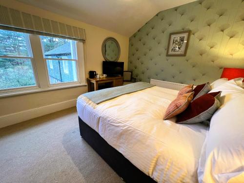 a bedroom with a bed and a large window at Ravenstone Lodge Country House Hotel in Keswick