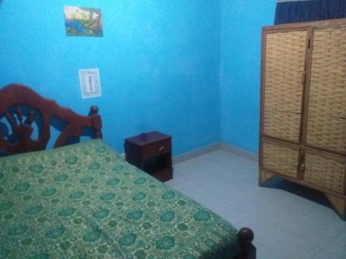 een slaapkamer met blauwe muren en een bed en een dressoir bij Hostel Mami Cruz in Cachí